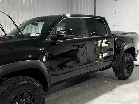 Glossy black Ram truck with fresh, reflective paint in a garage
